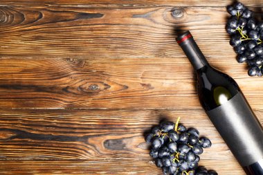 Kırmızı vintage açılmamış şişe boş mat siyah etiket ile şarap ve ahşap masa arka plan üzerinde Olgun üzüm demet. Pahalı bir şişe cabernet sauvignon kavramı. Alan, en iyi görünüm düz lay kopyalama