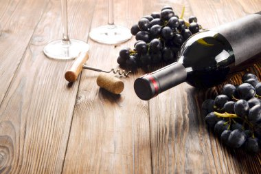 Vintage boş mat siyah etiketli, kırmızı şarap şişe düşünüp ve ahşap masa arka plan üzerinde üzüm demet. Pahalı bir şişe cabernet sauvignon kavramı. Kopyalama alanı, üstten görünüm, düz lay.