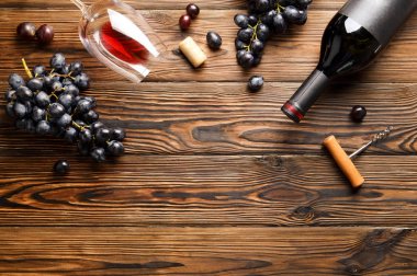 Vintage boş mat siyah etiketli, kırmızı şarap şişe düşünüp ve ahşap masa arka plan üzerinde üzüm demet. Pahalı bir şişe cabernet sauvignon kavramı. Kopyalama alanı, üstten görünüm, düz lay.
