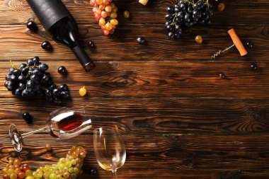 Vintage boş mat siyah etiketli, kırmızı şarap şişe düşünüp ve ahşap masa arka plan üzerinde üzüm demet. Pahalı bir şişe cabernet sauvignon kavramı. Kopyalama alanı, üstten görünüm, düz lay.