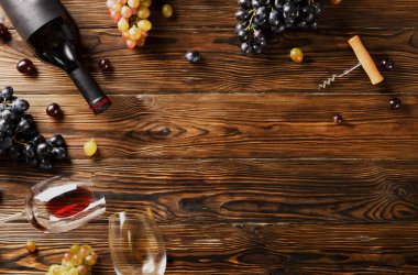 Vintage boş mat siyah etiketli, kırmızı şarap şişe düşünüp ve ahşap masa arka plan üzerinde üzüm demet. Pahalı bir şişe cabernet sauvignon kavramı. Kopyalama alanı, üstten görünüm, düz lay.