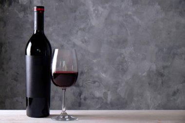 Vintage şişe boş mat siyah etiketli, ahşap masa, beton duvar arka plan üzerinde üzüm demet kırmızı şarap. Pahalı bir şişe cabernet sauvignon kavramı. Kopyalama alanı, üstten görünüm, düz lay.