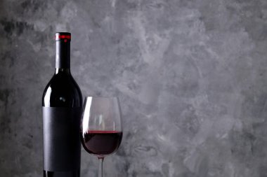 Vintage şişe boş mat siyah etiketli, ahşap masa, beton duvar arka plan üzerinde üzüm demet kırmızı şarap. Pahalı bir şişe cabernet sauvignon kavramı. Kopyalama alanı, üstten görünüm, düz lay.