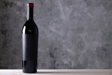 Vintage bir şişe kırmızı şarap ile boş mat siyah labe ahşap masa, beton duvar arka plan üzerinde. Pahalı bir şişe cabernet sauvignon kavramı. Kopya alanı, üstten görünüm, yakın çekim.