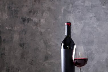 Vintage şişe boş mat siyah etiketli, ahşap masa, beton duvar arka plan üzerinde üzüm demet kırmızı şarap. Pahalı bir şişe cabernet sauvignon kavramı. Kopyalama alanı, üstten görünüm, düz lay.