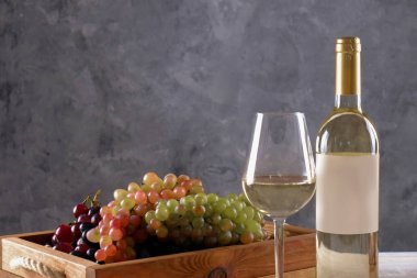 Vintage şişe boş mat etiketi, ahşap masa, beton arka plan üzerinde farklı üzüm demet beyaz şarap. Shardonnay kavramı pahalı bir şişe. Alan, en iyi görünümü kopyalayın, lay düz, yakın çekim.