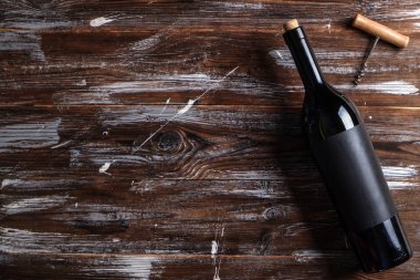 Vintage şişe boş mat siyah etiketli, tirbuşon grunged ahşap masa arka plan üzerinde kırmızı şarap. Pahalı bir şişe cabernet sauvignon kavramı. Kopyalama alanı, üstten görünüm, düz lay.
