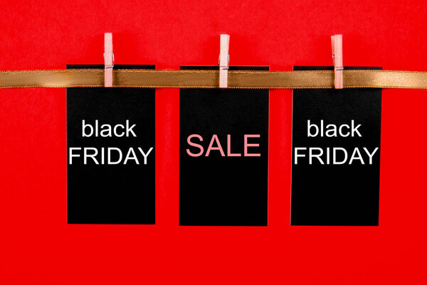 Black friday sale concept. Fourth Friday of November, beginning of Christmas shopping season since 1952. Black tag with white text on bright red background. Copy space, close up, top view, flat lay.