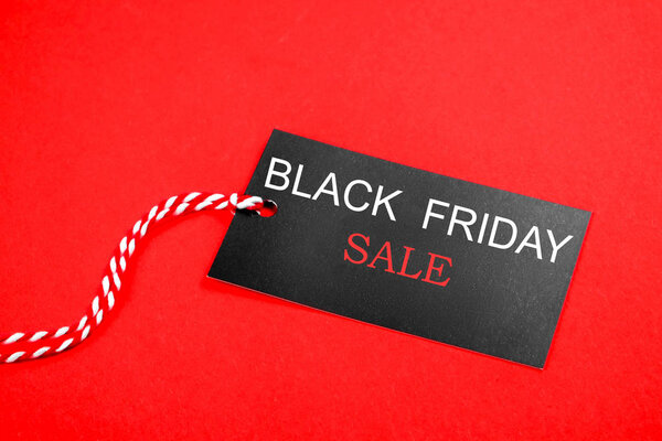 Черная пятница распродажа концепции. Четвертая пятница ноября, начало рождественского торгового сезона с 1952 года. Черный тэг с белым текстом на ярко-красном фоне. Копировальное пространство, крупный план, вид сверху, плоская кладка
.