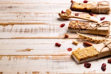 Çeşitli granola çikolata enerji barlar satırda dağınık karışık Kuruyemiş, tahıllar ve kuru meyve, grunged Beyaz ahşap masa arka plan ile. Sağlıklı vegan fitness gıda aperatif. Üstten Görünüm, kopya alanı, kapat.