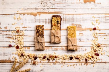 Çeşitli granola çikolata enerji barlar satırda dağınık karışık Kuruyemiş, tahıllar ve kuru meyve, grunged Beyaz ahşap masa arka plan ile. Sağlıklı vegan fitness gıda aperatif. Üstten Görünüm, kopya alanı, kapat.