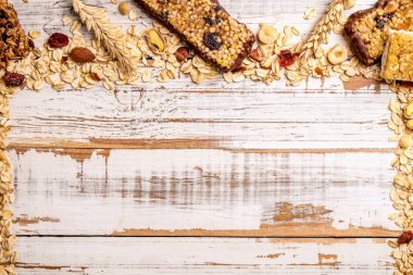 Çeşitli granola çikolata enerji barlar satırda dağınık karışık Kuruyemiş, tahıllar ve kuru meyve, grunged Beyaz ahşap masa arka plan ile. Sağlıklı vegan fitness gıda aperatif. Üstten Görünüm, kopya alanı, kapat.