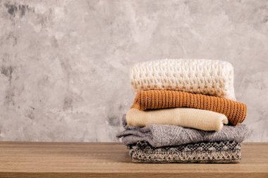 Örme sıcak pastel renk kazak, örgü desenleri dağınık yığın kahverengi ahşap masa, beton doku duvar arka plan üzerinde katlanmış farklı grup. Sonbahar Kış sezonunda Triko. Yakın çekim, alanı Kopyala