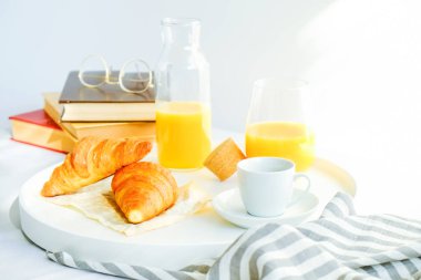 Yatakta, bardak taze portakal suyu, kahve ve Fransız kruvasan, vintage gözlükleri ve Kitaplar, fincan beyaz tepsi sabah kahvaltı battaniye çıkardı. Üstten görünüm, arka plan, kapatmak, alanı Kopyala.