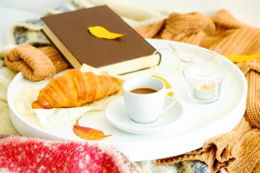 Yatakta, sabah kahvaltı kahve tepsisiyle beyaz ve Fransız kruvasan, vintage gözlükleri ve kitap, sarı sonbahar yaprakları, Kasım ruh hali. Üstten görünüm, arka plan, kapatmak, alanı Kopyala.