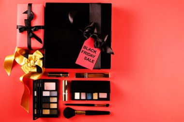 Siyah Cuma satış konsepti. Maskara öğeleri kümesini kadınlar için. Pastel renk ve allık fırçası, göz farı palet. Kırmızı etiketi ile parlak kırmızı bir arka plan üzerinde siyah metin. Uzay kopyalayın, üstten görünüm, düz yatıyordu yakın.