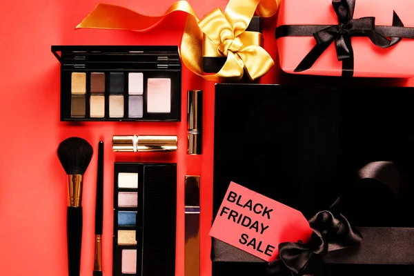 Siyah Cuma satış konsepti. Maskara öğeleri kümesini kadınlar için. Pastel renk ve allık fırçası, göz farı palet. Kırmızı etiketi ile parlak kırmızı bir arka plan üzerinde siyah metin. Uzay kopyalayın, üstten görünüm, düz yatıyordu yakın.