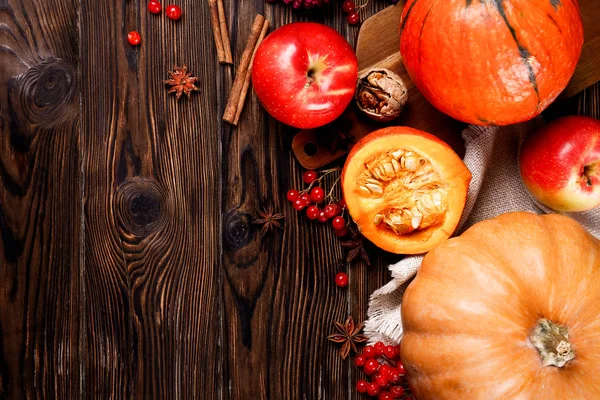 Thanksgiving background concept. Local produce pumpkin, apples & autumn leaves with other fruits, berries & vegetables for decoration on wood textured table. Close up, copy space, top view, flat lay.