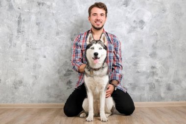 Genç sakallı adam dışarı asılı dışarı ile onun husky köpek. Hippi erkek damalı pazen gömlek ve gri dört bacaklı evde beslenen hayvan arkadaş ile kaliteli zaman geçirmek tişört giyiyor. Yakın çekim, uzay, arka plan kopya