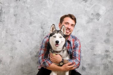 Genç sakallı adam dışarı asılı dışarı ile onun husky köpek. Hippi erkek damalı pazen gömlek ve gri dört bacaklı evde beslenen hayvan arkadaş ile kaliteli zaman geçirmek tişört giyiyor. Yakın çekim, uzay, arka plan kopya