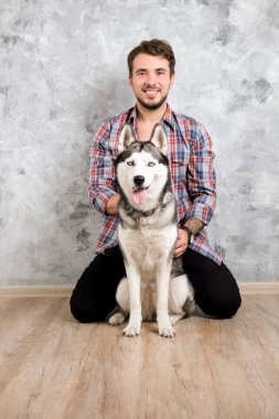 Genç sakallı adam dışarı asılı dışarı ile onun husky köpek. Hippi erkek damalı pazen gömlek ve gri dört bacaklı evde beslenen hayvan arkadaş ile kaliteli zaman geçirmek tişört giyiyor. Yakın çekim, uzay, arka plan kopya