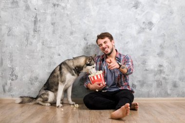 Genç sakallı adam dışarı asılı dışarı ile onun husky köpek. Hippi erkek damalı pazen gömlek ve gri dört bacaklı evde beslenen hayvan arkadaş ile kaliteli zaman geçirmek tişört giyiyor. Yakın çekim, uzay, arka plan kopya