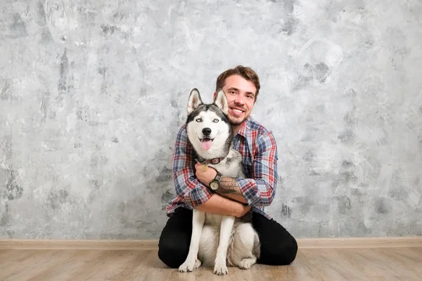 Genç sakallı adam dışarı asılı dışarı ile onun husky köpek. Hippi erkek damalı pazen gömlek ve gri dört bacaklı evde beslenen hayvan arkadaş ile kaliteli zaman geçirmek tişört giyiyor. Yakın çekim, uzay, arka plan kopya