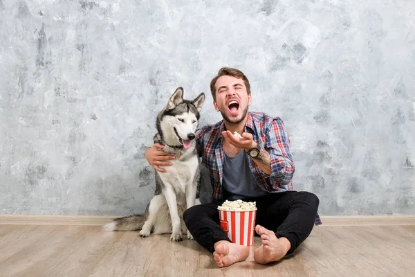 Young bearded man hanging out out with his husky dog. Hipster male wearing checkered flannel shirt and grey tank top spending quality time with four legged pet friend. Close up, copy space, background
