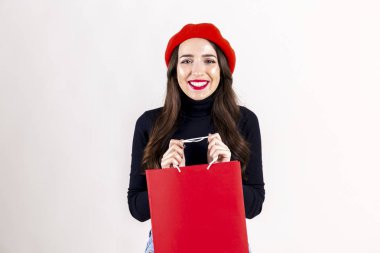 Siyah boğazlı kazak, kot anne ve kırmızı bere, boş alışveriş çantası elinde giyen güzel hipster genç kadın parlak kırmızı ruj makyaj ile. Sonbahar tatil Satılık sezon kavramı. Arka plan, kopya alanı