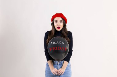 Balıkçı yaka, Anne kot ve kırmızı bere, giyen güzel hipster genç kadın ile parlak kırmızı ruj makyaj, helyum balon, siyah Cuma metni tutarak. Tatil kutlama kavramı. Arka plan, kopya alanı