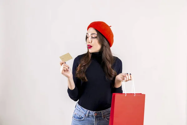 美丽的时髦的年轻妇女与明亮的红色口红妆 穿着黑色高领 妈妈牛仔裤和红色贝雷帽 拿着空白购物袋 秋季假期销售季节概念 复制空间 — 图库照片