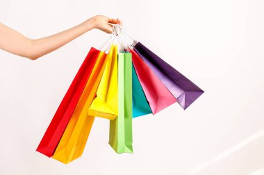 Farklı renkli boş alışveriş torbaları demet izole beyaz arka plan üzerinde tutan el atış kırpılmış. Kadının kollarında sayıda paketi ile. Siyah Cuma satış konsepti. Uzay kopyalayın, yakın çekim.