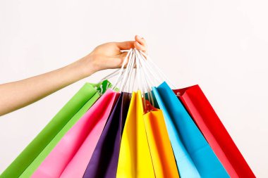 Farklı renkli boş alışveriş torbaları demet izole beyaz arka plan üzerinde tutan el atış kırpılmış. Kadının kollarında sayıda paketi ile. Siyah Cuma satış konsepti. Uzay kopyalayın, yakın çekim.