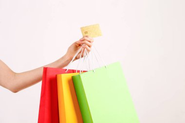 Farklı renkli boş alışveriş torbaları altın sınırsız kredi kartı ile demet izole beyaz arka plan üzerinde tutan el atış kırpılmış. Siyah Cuma satış konsepti. Uzay kopyalayın, yakın çekim.