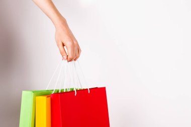 Farklı renkli boş alışveriş torbaları demet izole beyaz arka plan üzerinde tutan el atış kırpılmış. Kadının kollarında sayıda paketi ile. Siyah Cuma satış konsepti. Uzay kopyalayın, yakın çekim.
