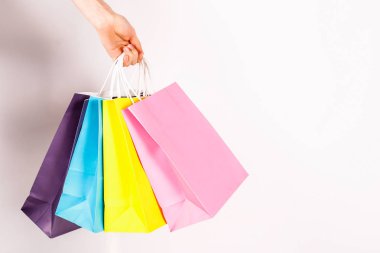 Farklı renkli boş alışveriş torbaları demet izole beyaz arka plan üzerinde tutan el atış kırpılmış. Kadının kollarında sayıda paketi ile. Siyah Cuma satış konsepti. Uzay kopyalayın, yakın çekim.