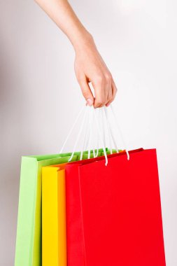 Farklı renkli boş alışveriş torbaları demet izole beyaz arka plan üzerinde tutan el atış kırpılmış. Kadının kollarında sayıda paketi ile. Siyah Cuma satış konsepti. Uzay kopyalayın, yakın çekim.