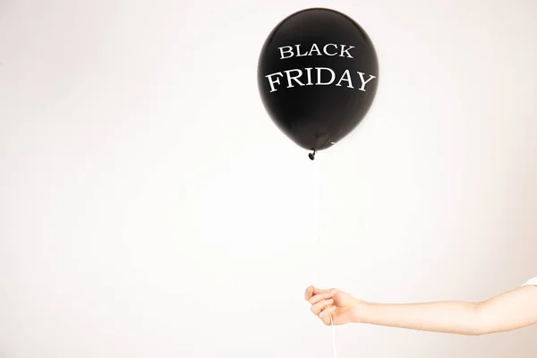 Black Friday on black balloon in girl\'s hand. Black friday sale concept. Fourth Friday of November, beginning of Christmas shopping season since 1952. Copy space, close up, top view, flat lay.