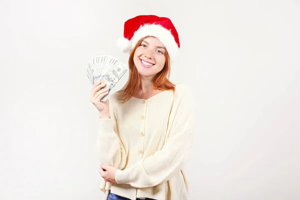 Money as a Christmas present concept. Portrait of happy young redheaded woman holding bunch of one hundred dollar bills received as new years gift. White isolated background, copy space, close up. — Stock Photo, Image