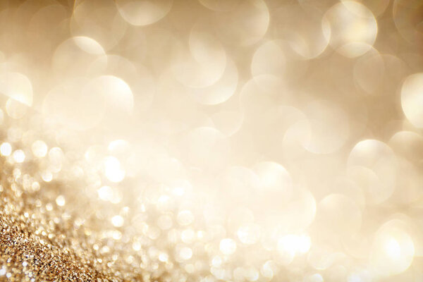 Golden sparkle glitters with bokeh effect and selectieve focus. Festive background with bright gold lights, champagne bubble. Christmas mood concept. Copy space, close up, texture, top view.