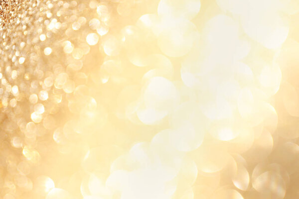 Golden sparkle glitters with bokeh effect and selectieve focus. Festive background with bright gold lights, champagne bubble. Christmas mood concept. Copy space, close up, texture, top view.
