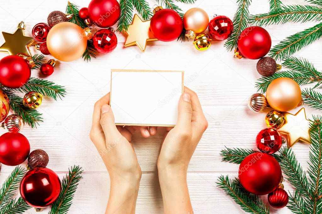 Female hands writing letter to Santa Claus on wooden background with christmas gifts and decoration top view. Vintage toned image with woman, wish list for christmas, flat lay, copy space, background.