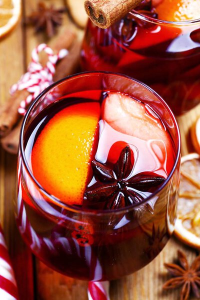 Christmas composition with mulled wine with its ingredients & spices on wooden textured table. Traditional drink on winter holiday season. Copy space, close up, top view, background.