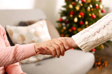 Yaşlı kadın kutlama Noel evde, süslü tatil çam ağacı üzerinde arka plan ile. Huzurevi yaşlı kadına. Yakın çekim, atış kırpılmış alanı Kopyala.