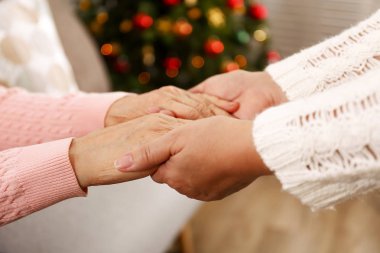 Yaşlı kadın kutlama Noel evde, süslü tatil çam ağacı üzerinde arka plan ile. Huzurevi yaşlı kadına. Yakın çekim, atış kırpılmış alanı Kopyala.