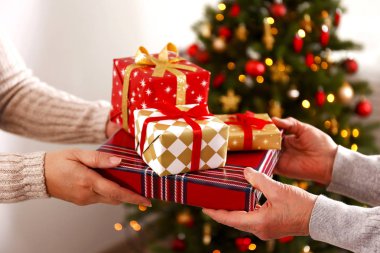 Yaşlı kadın kutlama Noel evde, süslü tatil çam ağacı üzerinde arka plan ile. Huzurevi yaşlı kadına. Yakın çekim, atış kırpılmış alanı Kopyala.