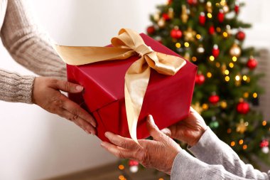 Yaşlı kadın kutlama Noel evde, süslü tatil çam ağacı üzerinde arka plan ile. Huzurevi yaşlı kadına. Yakın çekim, atış kırpılmış alanı Kopyala.