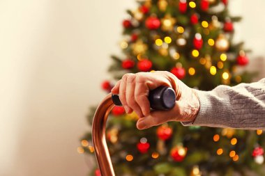 Yaşlı kadın kutlama Noel evde, süslü tatil çam ağacı üzerinde arka plan ile. Huzurevi yaşlı kadına. Yakın çekim, atış kırpılmış alanı Kopyala.