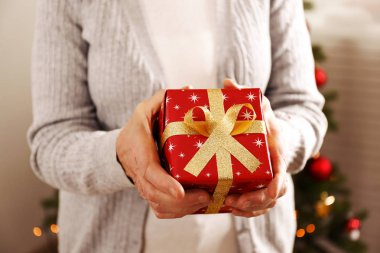 Yaşlı kadın kutlama Noel evde, süslü tatil çam ağacı üzerinde arka plan ile. Huzurevi yaşlı kadına. Yakın çekim, atış kırpılmış alanı Kopyala.