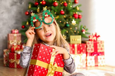 Portre sevimli mutlu beş yaşındaki kızın birçok alan sunar, zemin üzerine sarılmış hediyeler yığını ile süslenmiş Noel ağacı. Yakın çekim, alanı Kopyala.